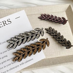 Detailed macro view of four leaf-shaped hair clips encrusted with sparkling rhinestones