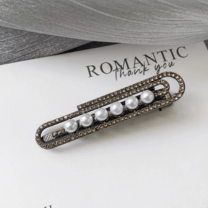 Détails des strass champagne et sept perles sur une barrette en métal gris foncé