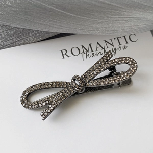 Vue macro de la pince à cheveux noeud en métal noir avec strass champagne foncé