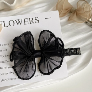 Detail of a black lace bow hair clip with sparkling rhinestones on an duckbill clip