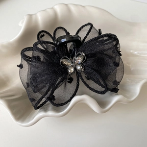 Detail of black mesh lace hair claw clip with sparkling crystal butterfly embellishment
