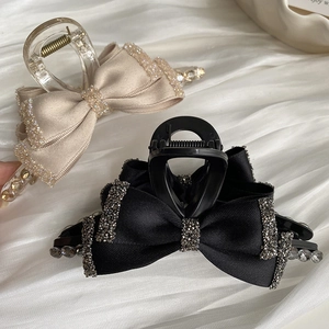 Detail showing elegant ribbon hair claws with rhinestones in black and champagne