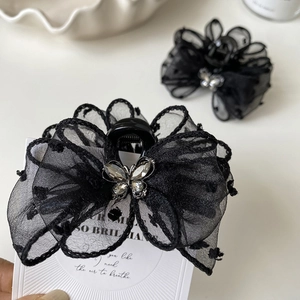 Detail of black mesh polka dot bow hair claw with sparkling butterfly rhinestone center