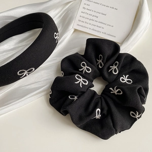Détail d'un ensemble serre-tête et chouchou noirs avec broderie de nœuds blancs