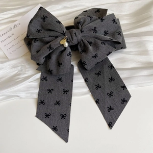 Detail of dark grey bow hair clip with black bow patterns and pearl pendant detail