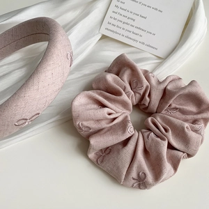 Détail de l'ensemble bandeau et chouchou rose pâle avec broderie de nœuds délicats