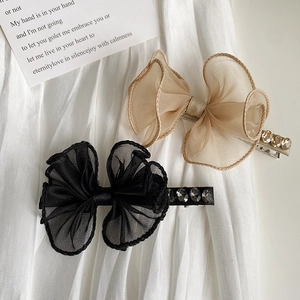 Close-up of lace bow hair clips with rhinestones in black and champagne organza fabric