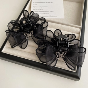 Gros plan sur des barrettes nœuds en maille noire avec papillons en strass étincelants