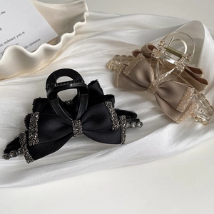 Detail of elegant black and beige bow hair claws with sparkling rhinestones on silk fabric