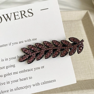 Detail of sparkling purple crystal wheat leaf hair clip on vintage card background