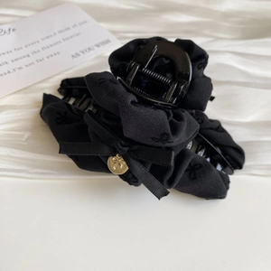 Close-up of black fabric hair claw clip with bow ribbon and golden butterfly pendant