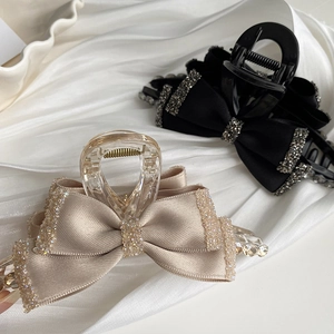 Detail of elegant satin bow hair claws with sparkling rhinestone edges in champagne and black