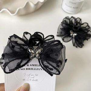 Close-up of black lace bow hair claw clip with crystal butterfly and silver metal detail