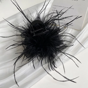 Detailed view of black ostrich feather hair claw clip with mesh on white fabric