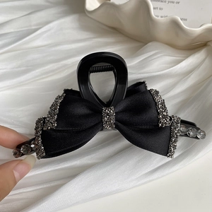 Detailed macro shot of elegant black bow hair claw clip with rhinestones and grey beads