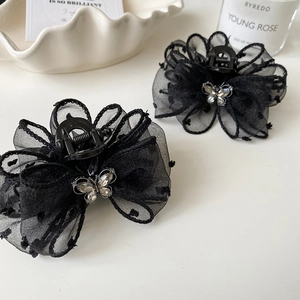 Detail of black mesh polka dot bow hair claw clip with a sparkling rhinestone butterfly