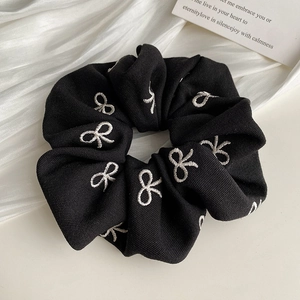 Détail du chouchou noir avec broderie de nœuds blancs et texture de coton de qualité
