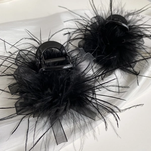 Detail of fluffy black ostrich feathers and mesh bow on elegant shark hair clips