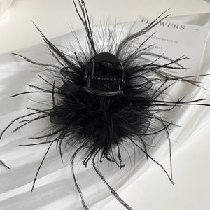 Detailed view of elegant black feather hair claw clip with mesh on white silk cloth