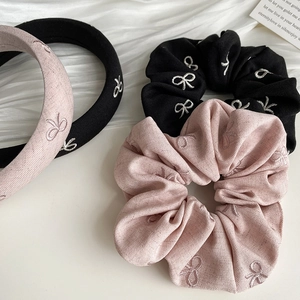 Détail d'un ensemble de serre-tête et chouchou avec broderie nœud en rose et noir