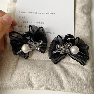 Detail of elegant black mesh bow hair clips with rhinestones and pearl accents