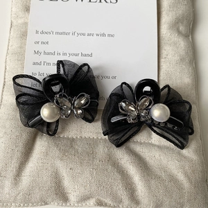Detail of elegant black mesh bow hair clips with white pearls and sparkling rhinestones