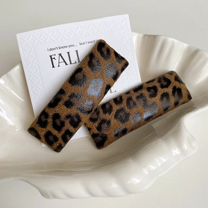 Close-up of leopard print rectangular hair clips with soft velvet texture in shell dish