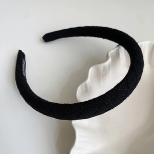 Detail of black fabric headband with diamond quilted texture and Handmade woven label