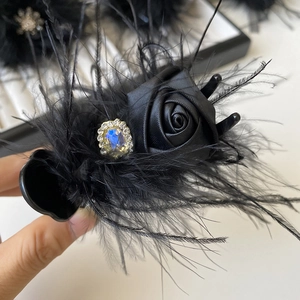 Detailed macro view of a vintage black satin rose hair claw with feathers and jewels