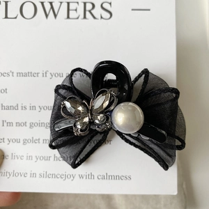 Detail of elegant black mesh bow hair claw clip with rhinestones and large pearl