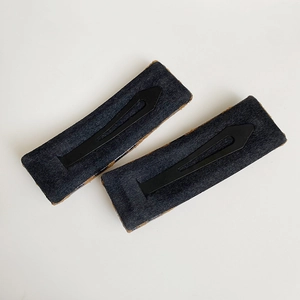 Pair of gray felt rectangular BB hair clips with black metal spring clips on beige background