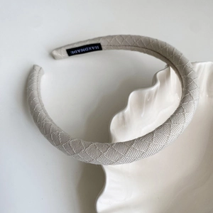 Close-up of beige fabric headband with quilted diamond pattern and handmade label