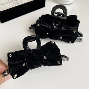 Close-up of black velvet bow hair claws with sparkling rhinestones on a white surface