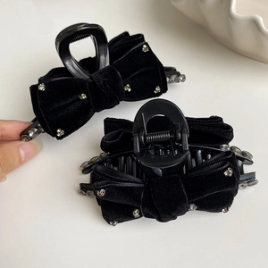 Elegant black velvet bow hair claw clip with silver rhinestones on a white shell background