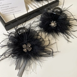 Close-up of black feather hair claw clip with mesh layer and sparkling rhinestone detail