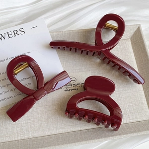 Three-piece deep wine red hair claw set featuring elegant glossy shark clips on beige tray