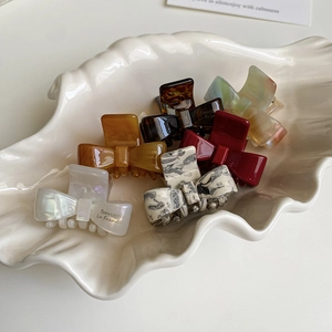 Set aus sieben farbenfrohen 4cm Acetat Schleifen-Haarklammern in einer weißen Schale