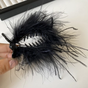 Detail of elegant black feather hair claw clip held by hand to show 8cm size and texture