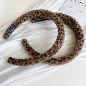 Detail shot of leopard print faux fur headband showing the woven HAND MADE label