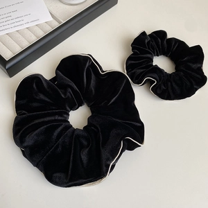 Détail de deux chouchous en velours noir à bords dorés en tailles grande et petite