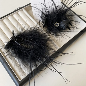 Detail of luxury black feather hair clips with rhinestones in a white velvet jewelry box