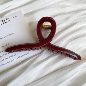 Detail of burgundy twist claw clip on white fabric with artistic greeting card