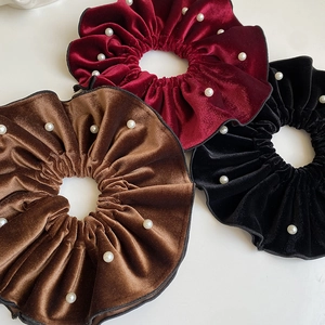 Detail of velvet scrunchies with white pearls in burgundy, brown and black colors