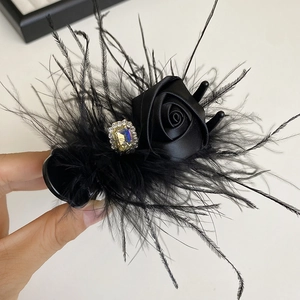 Detail of gothic black feather hair clip with satin rose and yellow gemstone decoration