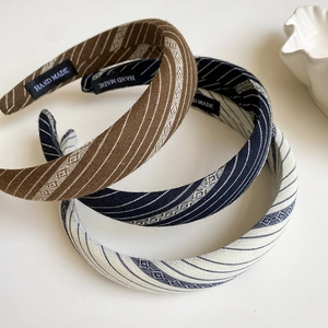Detail of three striped fabric headbands in brown, navy, and beige with handmade labels