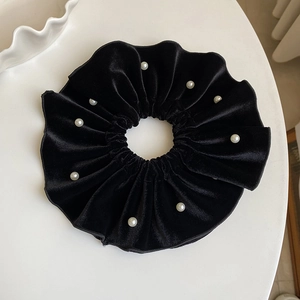 Detail of oversized black velvet scrunchie featuring elegant white faux pearl accents