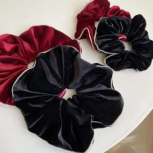 Détail de chouchous en velours bordeaux et noir avec des bords métalliques