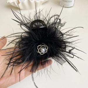 Detail of elegant black feather hair claw clip with a silver camellia flower bead