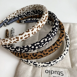Close-up of leopard print fabric headbands with handmade tags on a beige linen bag