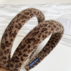 Close-up of leopard print faux fur headband with a handmade label on soft silk background